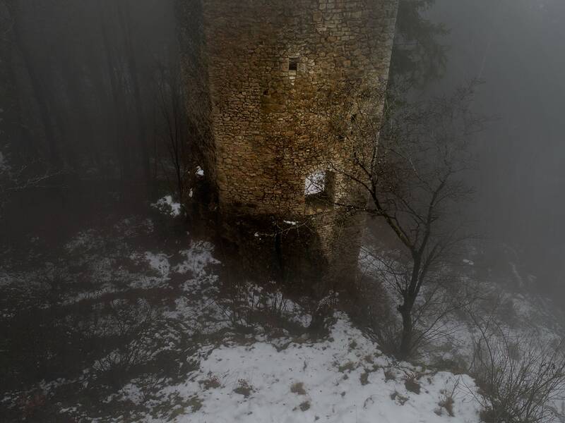 Blick auf die Ruine Hohenerpfingen aus der Luft, umgeben von kahlen Bäumen, Schnee und Nebel im Winter.