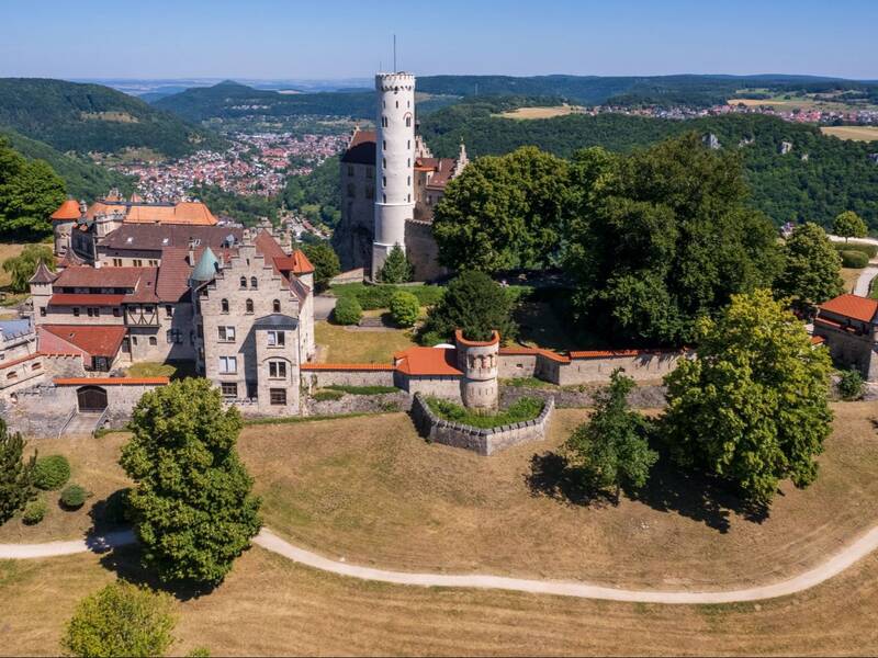 Blick auf Schloss Lichtenstein aus der Luft. Im Vordergrund ist die Mauer zu sehen.