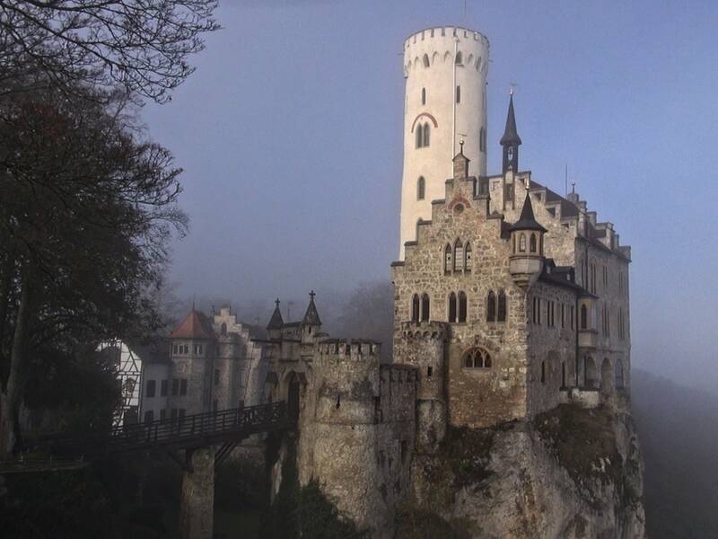 Blick auf Schloss Lichtenstein aus der Luft bei leichtem Nebel und dem Wilhelmsturm im Vordergrund.