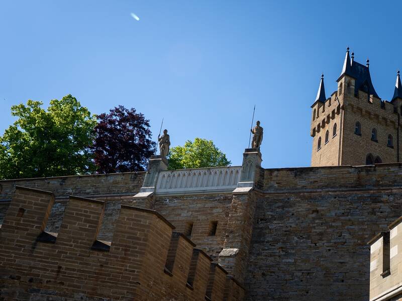 Torwächter über der Tunneleinfahrt mit Torturm der Burg Hohenzollern im Hintergrund.
