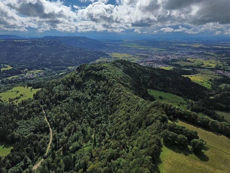 Blick Richtung Plettenberg auf den Burgfelsen der Burg Schalksburg mit teilrekonstruiertem Bergfried. Im linken Bildbereich ist die Gemeinde Laufen zu erkennen.